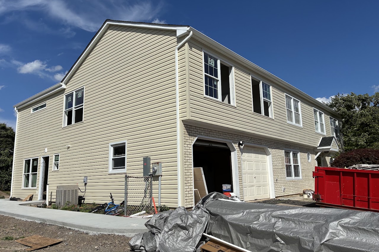 A completed house in pale siding with two garage doors and a new driveway