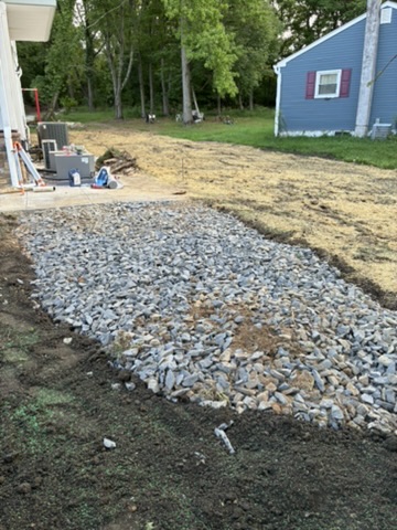 A long bed of drainage stone laid along a freshly graded yard