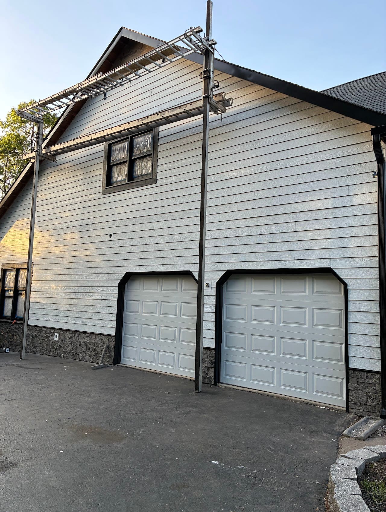 A two-bay garage in grey siding with a ladder rack along the roofline
