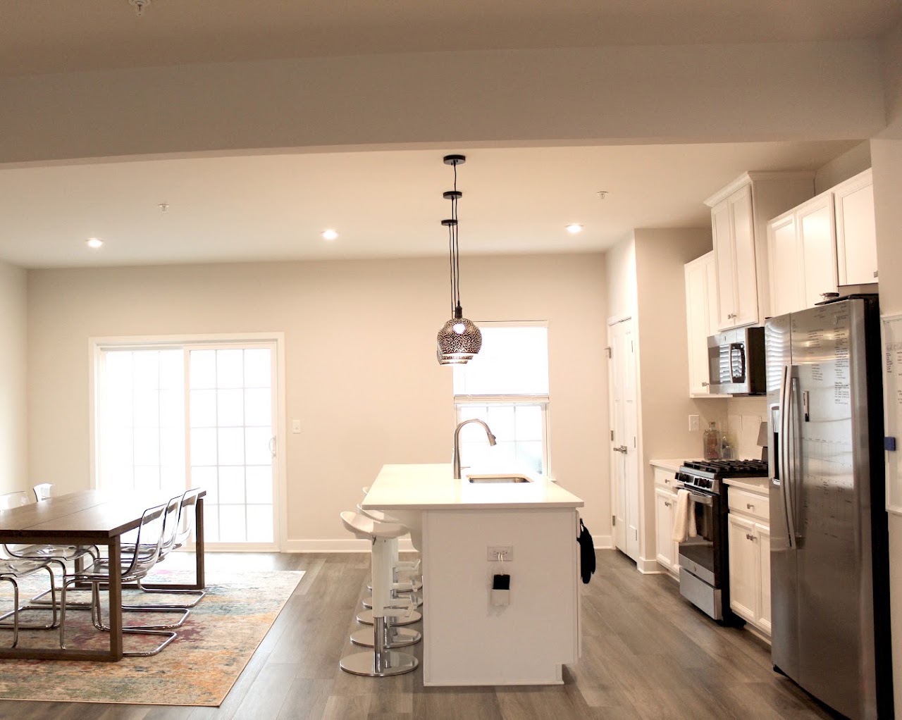 A finished open kitchen with a white island under a single glass pendant